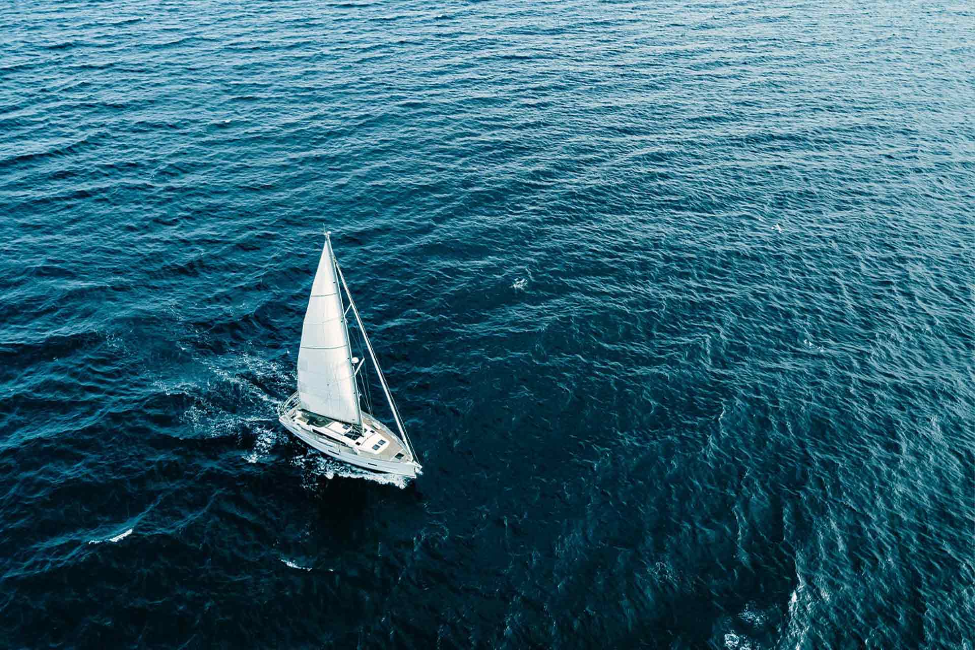 Fugleperspektiv av en seilbåt som glir over havet, med fokus på båt og forsikring fra waterCircles.