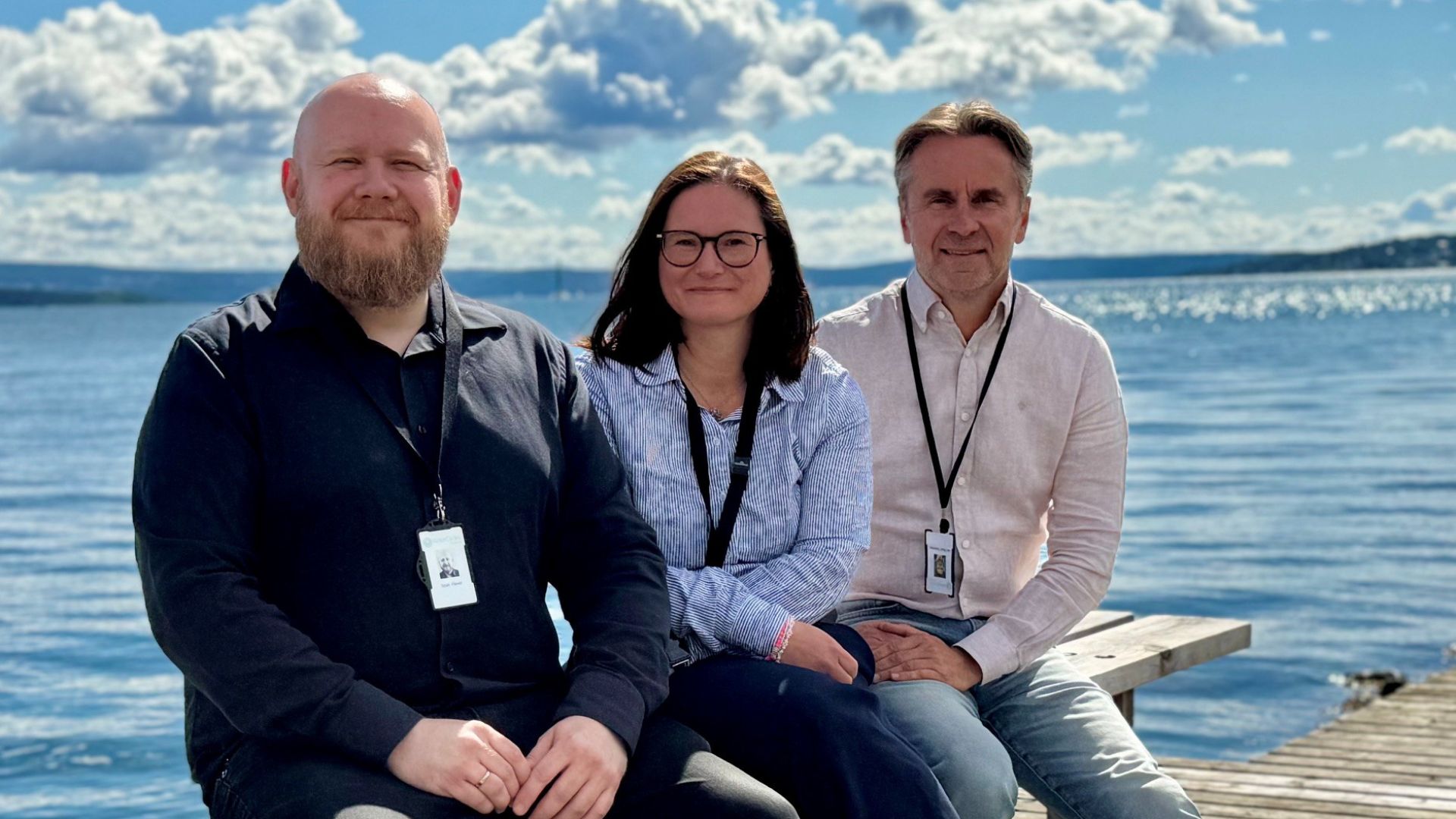 Tre medarbeidere i WaterCircles sitter på en brygge ved sjøen i forbindelse med utviklingen av AI-verktøyet Riskio.